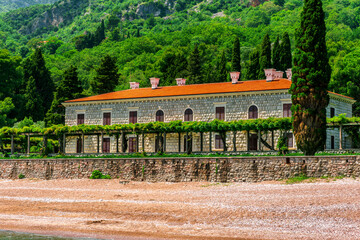 Wall Mural - beautiful summer season landscape of scenic coast with beach and nice architecture building of hotel or palace with awesome green garden and great mountains on background