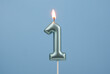 © Valerii Evlakhov - Burning blue birthday candle on blue background, number 1