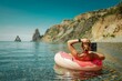 © svetograph - Woman laptop sea. Freelancer woman in sunglases floating on an inflatable big pink donut with a laptop in the sea. People summer vacation rest lifestyle concept