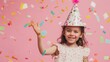 © VK Studio - A joyful child in a party hat amid colorful confetti, celebrating a birthday with excitement and delight against a pink backdrop.