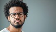 © Олександр Романюк - Man with curly hair and glasses expressing skepticism indoors against a gray background