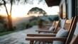© Maximages  - The photo shows an outdoor patio with a set of wooden chairs arranged neatly, overlooking a scenic view of the sunset, creating an inviting and relaxed outdoor atmosphere.