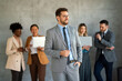 © NDABCREATIVITY - Portrait of successful business man, entrepreneur while multiethnic colleagues working background.
