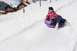 © Studio Peace - Happy child rides snow tubing (inflatable sled) in winter in the mountains.