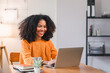 © PRIME STOCK LAB - Smiling African American woman using a laptop while working from home.