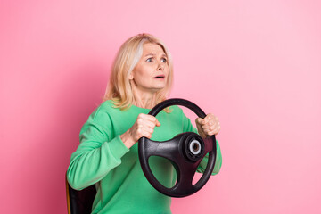 Sticker - Photo of attractive retired woman hold steering wheel driver scared dressed stylish green clothes isolated on pink color background