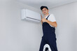 © Studio Peace - Professional technician gives a thumbs up and smiles after installing a modern air conditioner.