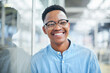 © TasJam/peopleimages.com - Happy, creative and face of black man at startup, designer and smile in office. Business, employee and portrait of businessman with glass wall, freelance agency or entrepreneur for pride in workplace