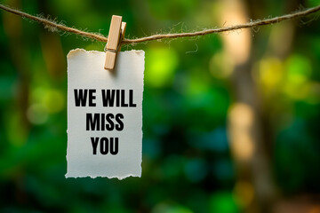 We will miss you message written on paper hung with clothespins. Conceptual we will miss you symbol. Copy space.