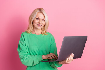 Sticker - Photo portrait of lovely senior lady hold netbook ecommerce dressed stylish green garment isolated on pink color background