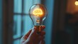 © kittikunfoto - A hand holding a light bulb with a glowing brain-shaped filament inside, symbolizing the concept of bright ideas and mental illumination.