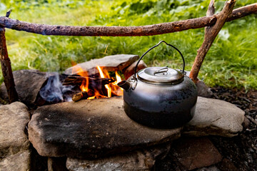 coffee pot on a campfire during a hike in the mountains.