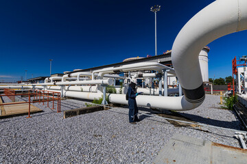 Canvas Print - Male worker inspection at steel long pipes and pipe elbow in station oil factory during refinery valve