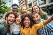 © Sirinporn - Diverse group of cheerful friends of different racial backgrounds gathered together, laughing and making funny faces while taking a playful selfie in urban surroundings.