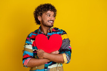 Sticker - Photo of handsome young male hold heart postcard look empty space dressed stylish colorful garment isolated on yellow color background