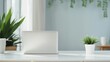 © อาริษา วันดี - A laptop is open on a desk with a potted plant and a stack of books