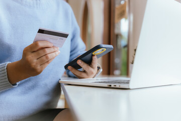 woman at home making online payments on her laptop. she holds her credit card and enters the details