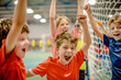 © Nomad_Soul - Children celebrating a goal in an indoor football sports facility. Generative AI