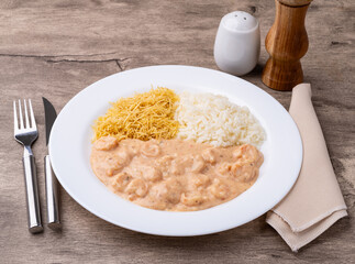 Wall Mural - Shrimp strogonoff with rice and straw potato over wooden table