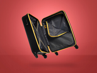 Wall Mural - Open empty suitcase in air on red background