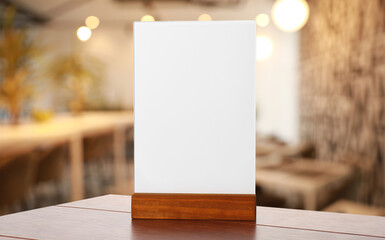 Wall Mural - Menu holder with blank card on wooden table in cafe. Mockup for design