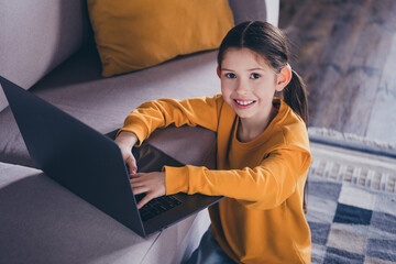 Canvas Print - Photo portrait of cute small girl sit couch netbook browsing dressed orange outfit cozy day light home interior living room