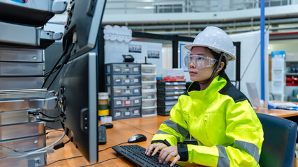 Inside the large Industry Factory Female Computer Engineer Works on Personal Computer She coding program for control machine,Thailand people work on fours monitors,Programmer working with serious