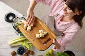 Sticker - Young woman making delicious smoothie with blender at white marble table in kitchen, top view