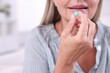 © New Africa - Senior woman taking pill at home, closeup