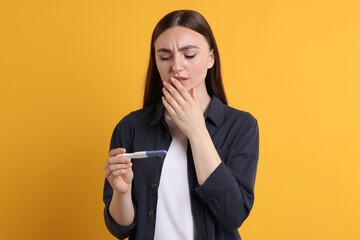 Sticker - Sad woman holding pregnancy test on orange background