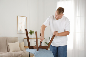 Wall Mural - Man with screwdriver assembling chair in room