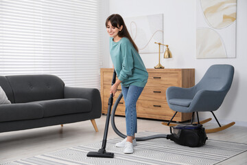 Poster - Young woman vacuuming carpet in living room