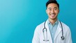 © Business Pics - Smiling asian man physician in a white coat on blue background.
