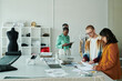 © pressmaster - Three young intercultural coworkers standing in spacious workshop and looking though online and paper sketches for new fashion collection