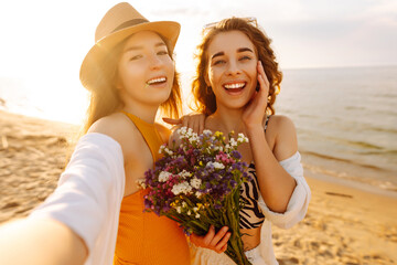 Wall Mural - Two pretty best friends women making selfie on beach, light and bright summer colors. Friends together. Travel, blogging, weekend, relax and lifestyle concept.