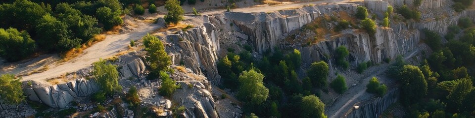 Sticker - Aerial perspective of a quarry featuring steep gray granite cliffs, partially obscured by trees and remnants of old rock deposits during a summer morning.