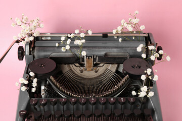 Wall Mural - Vintage typewriter with gypsophila flowers on pink background, closeup