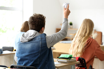 Canvas Print - Male student throwing crumpled paper in his classmates at classroom