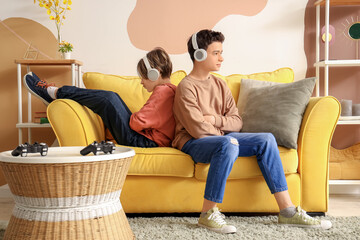 Wall Mural - Upset brothers in headphones after quarrel at home