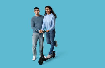 Poster - Happy young couple with modern electric kick scooter on blue background