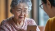 © klss777 - An elderly woman learns smartphone skills in a supportive tech class with a guiding instructor.