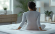 © GulArt - Rear view of a young woman sitting on the bed with white soft mattress inside of a modern room