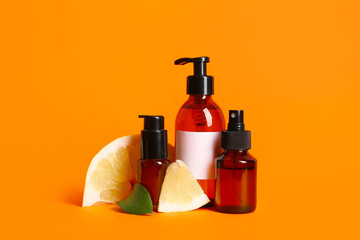 Wall Mural - Bottles of cosmetic product and pieces of fresh pomelo on orange background