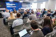 © Anton Gvozdikov - Business professionals attending a conference session with a panel discussion in progress. Diverse audience engaged in presentations.