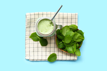 Wall Mural - Mason jar of fresh spinach smoothie on blue background