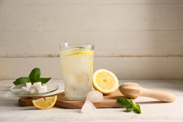 Wall Mural - Glass of fresh lemonade with mint and juicer on white wooden background