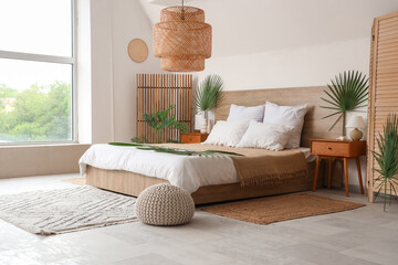 Poster - Large bed, bedside tables and pouf decorated with palm branches in bedroom