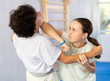 © JackF - Boy and girl paired up and practice to aim stroke to neutralize opponent and repulse attack. Class self-defense training in presence of experienced instructor