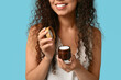 © Pixel-Shot - Beautiful young African-American woman with jar of face cream on blue background