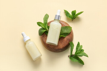 Wall Mural - Bottles of essential oil, wooden stand and mint leaves on beige background